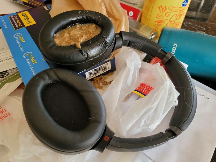 Headphones damaged with spilled liquid on cluttered surface, highlighting expensive accidents.