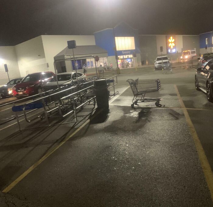 Shopping cart left in parking space at night, showcasing entitled behavior.