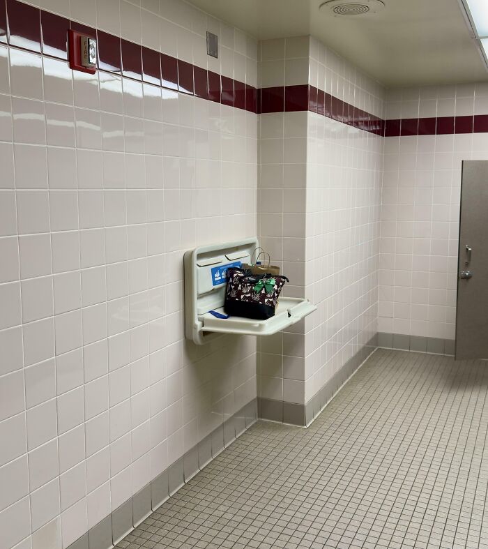 Entitled people leaving a large purse on a public changing table in an empty restroom.