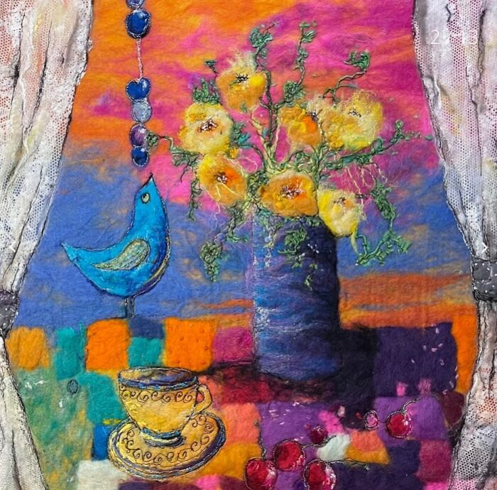 Fiber artwork of a vibrant vase, yellow flowers, and a blue bird by Moy Mackay.