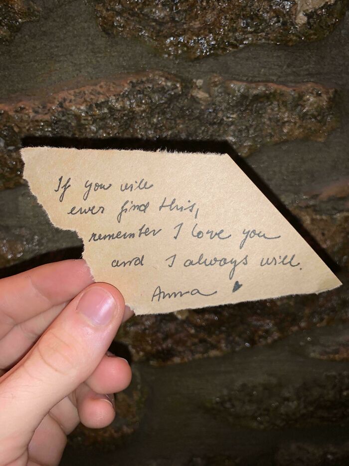 Hand holding a torn note with a heartfelt message, uncovering a hidden home discovery find.