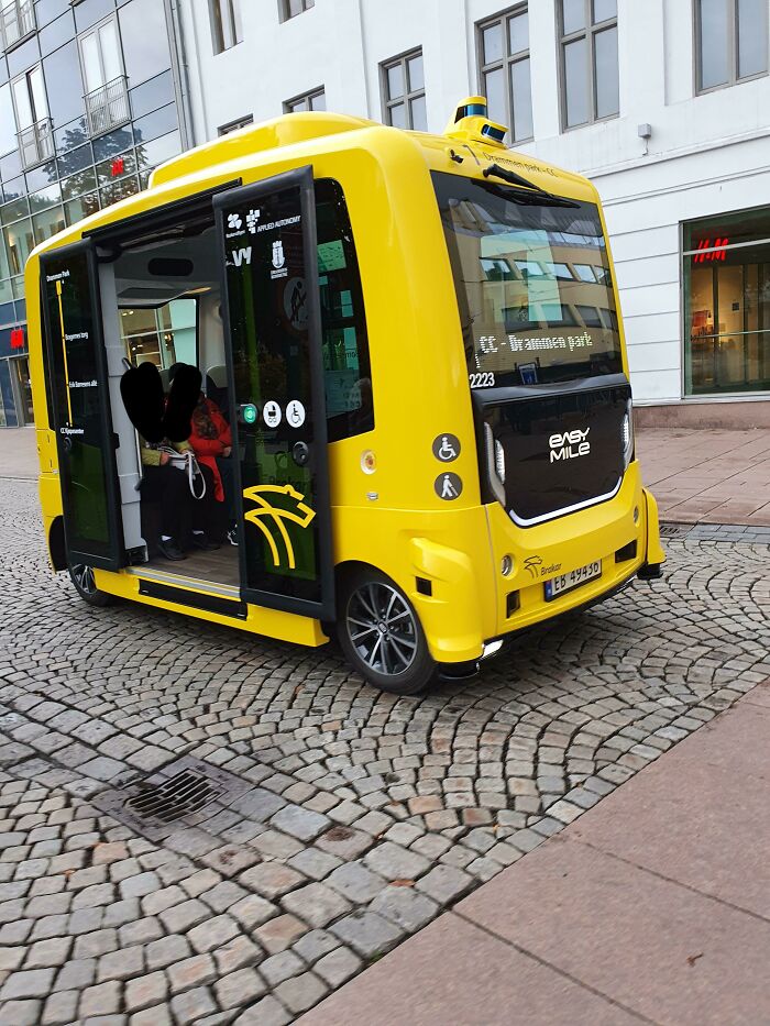 Yellow autonomous shuttle on a cobblestone street, exemplifying how countries care for their citizens with innovative transport solutions.