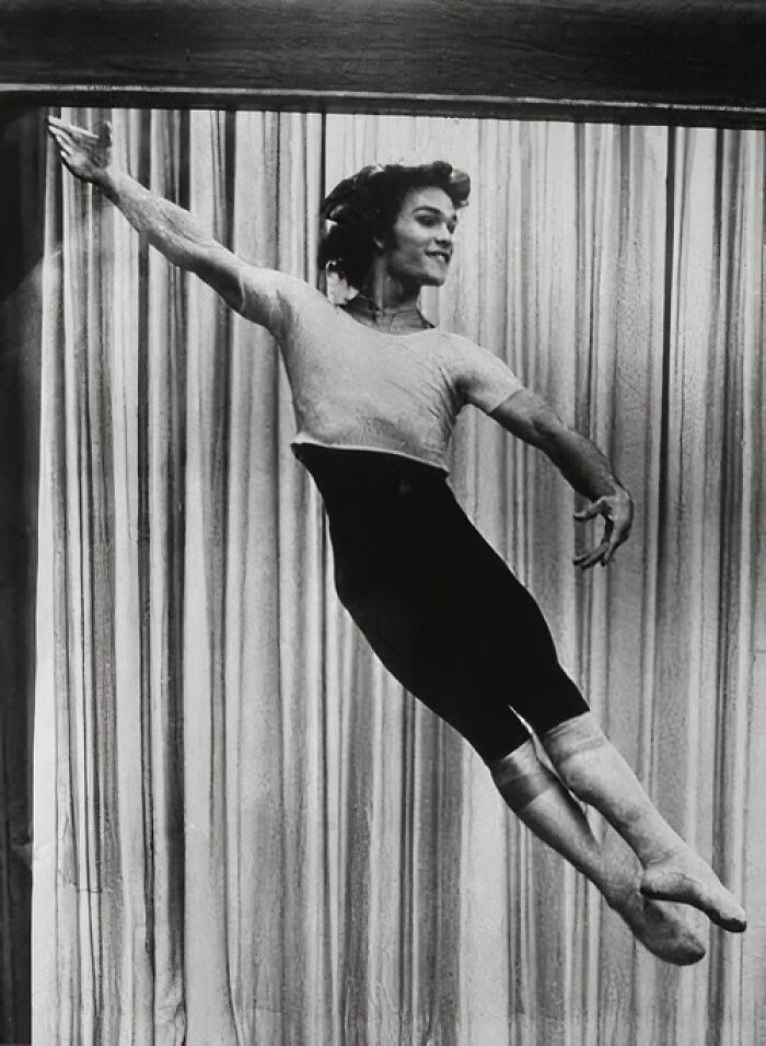 Ballet dancer mid-leap in front of curtains, representing forgotten corners of history.