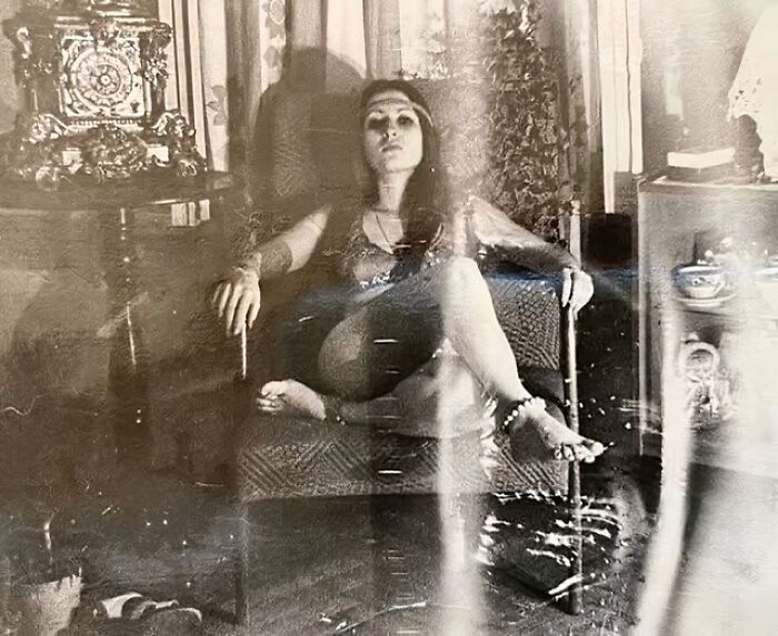 Woman sitting in an armchair, surrounded by vintage decor, capturing a forgotten corner of history.