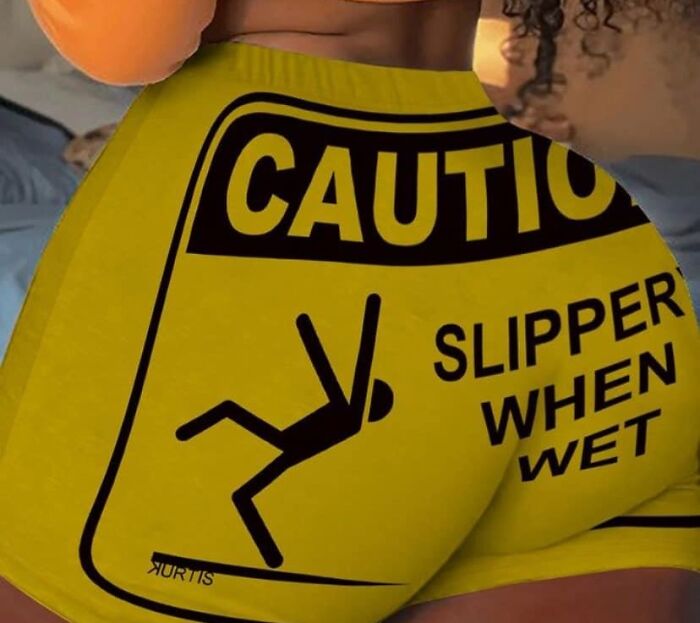 Yellow shorts with a "Caution: Slippery When Wet" sign print as a fashion disaster.