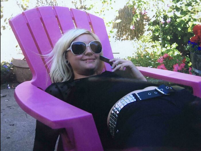 Young woman with blonde hair and sunglasses lying on a pink chair, showcasing a regrettable past photo moment outdoors.