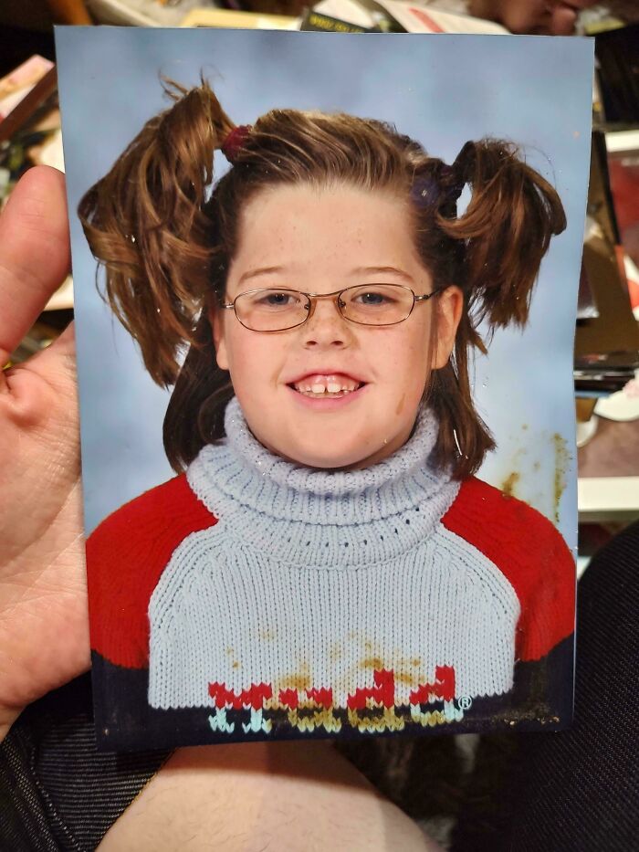 Photo of a child with glasses and pigtails wearing a stained knit sweater from a regrettable past.