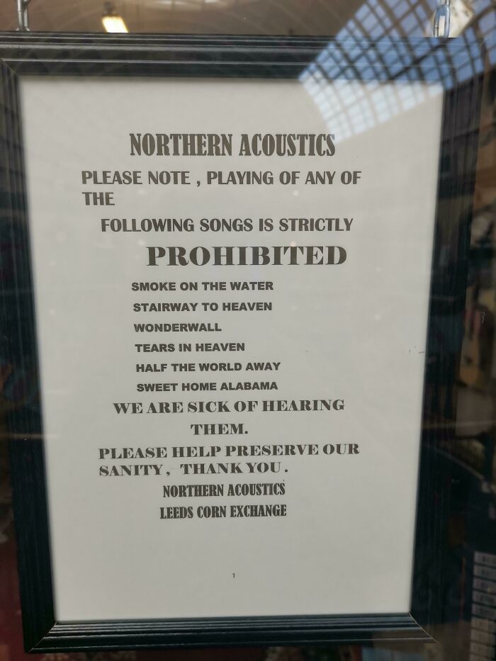 Sign listing prohibited songs in a humorous passive-aggressive tone at Northern Acoustics, Leeds Corn Exchange.