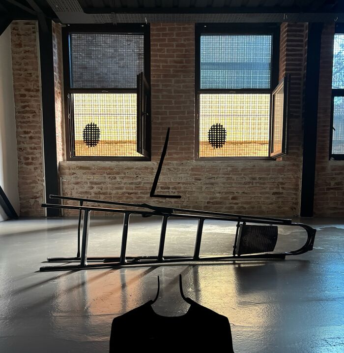 Creative illustration by Robin Yayla featuring a silhouetted figure and a tilted chair in front of a brick wall and windows.