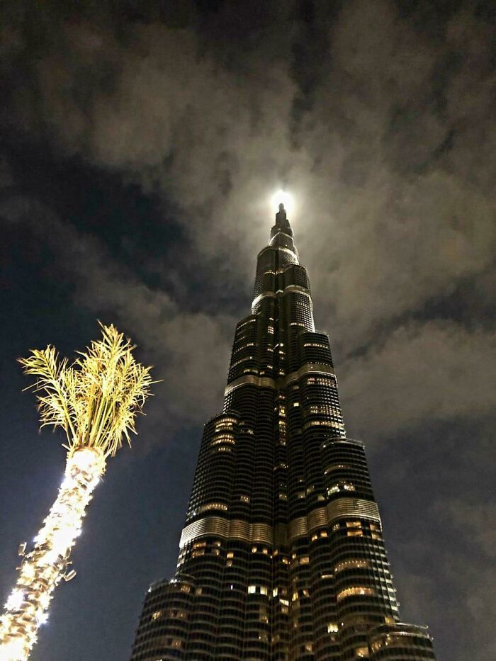 Burj Khalifa illuminated at night, showcasing Dubai's iconic skyline with dramatic moonlit clouds in the background.