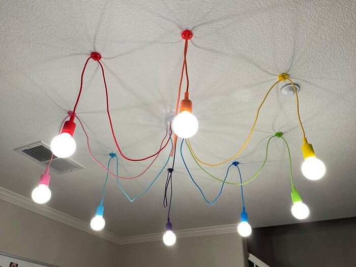 Colorful ceiling lights with red, orange, yellow, green, blue, and purple cords reminiscent of 90s kids decor.