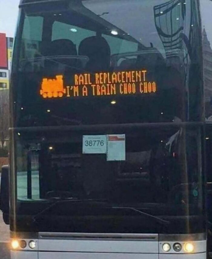 Bus with a humorous sign reading "Rail Replacement, I'm a Train Choo Choo," highlighting British humor.
