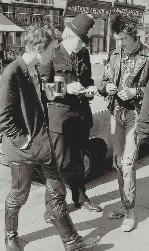 Punk rockers interacting with a police officer on a city street, representing an interesting historical moment in subculture history.