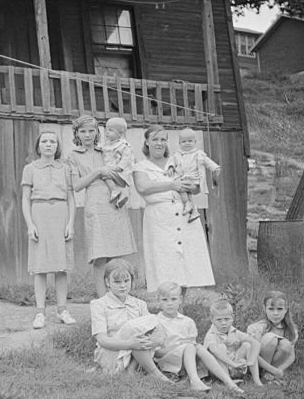 Familia posando afuera de una cabaña antigua, momento capturado en fotos históricas poco conocidas.