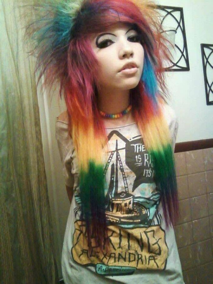 Teen with vibrant multicolored hair and heavy eyeliner wearing a band t-shirt in a cringe-worthy regrettable past photo.
