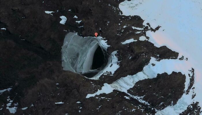 Aerial view of a large, mysterious hole in an icy landscape found on Google Earth.