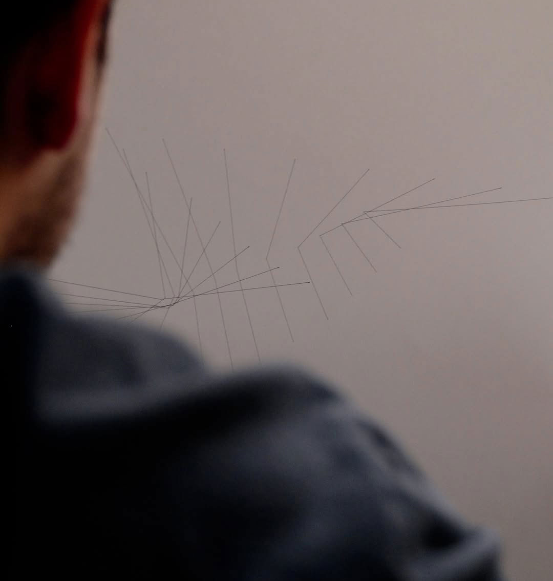 A person observes abstract lines on paper, symbolizing brain activity imprint in art.