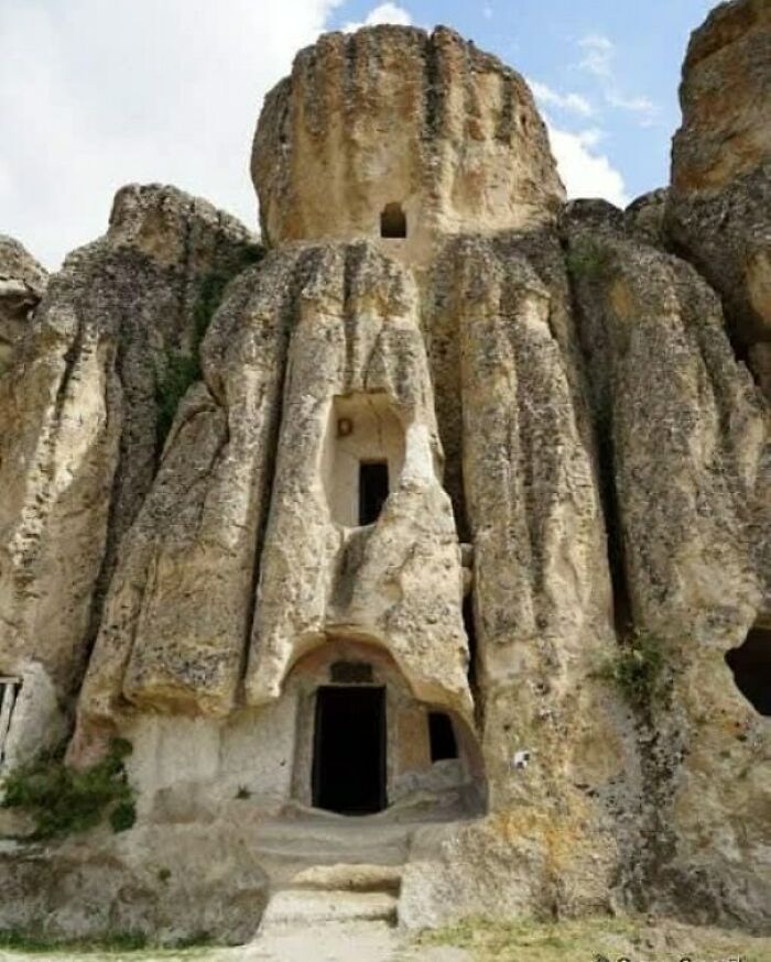 Ancient explorers' cave dwellings carved into a large rock formation with multiple entrances.