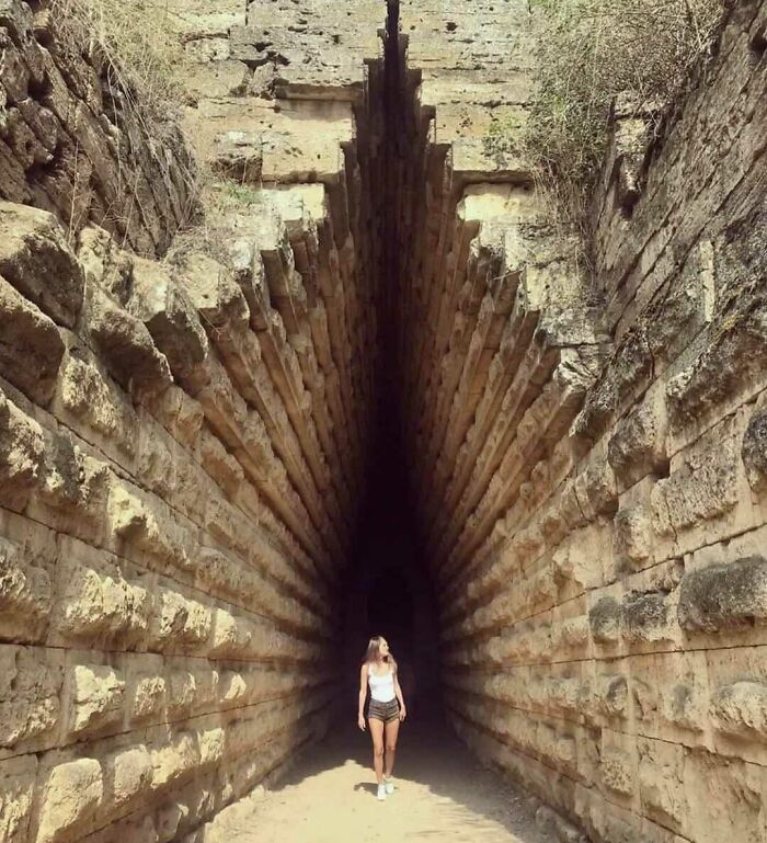 Person walking in an ancient stone corridor with deep perspective, showcasing fascinating preserved architecture.