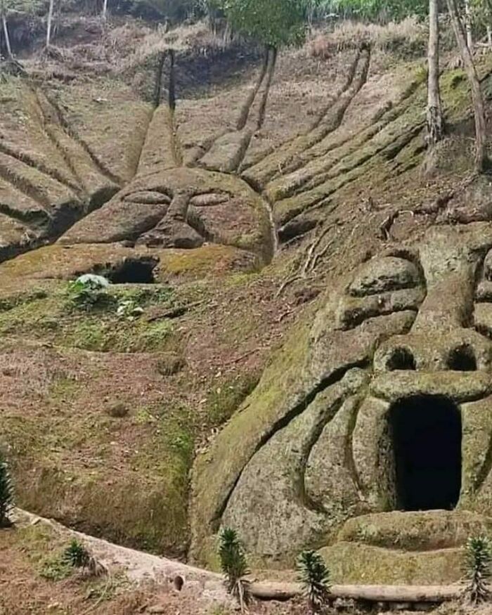 Stone carvings resembling faces in a hillside, preserved from ancient times, showcasing historical artistry.