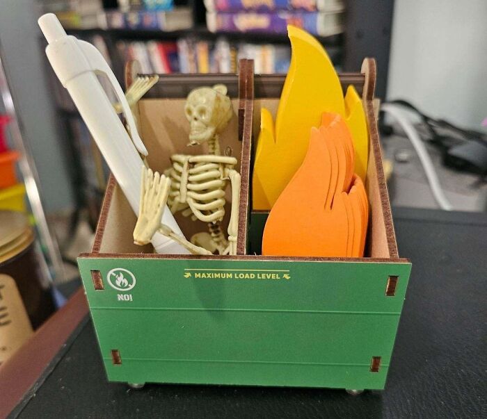 Genuine Fred quirky desk organizer with a skeleton, pen, and fire motif, placed on a classroom desk.