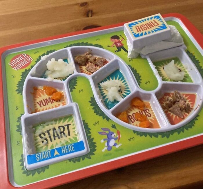 Genuine Fred Dinner Winner kids' tray with sections labeled Start, Yum, Bonus, Finish, partially filled with food.