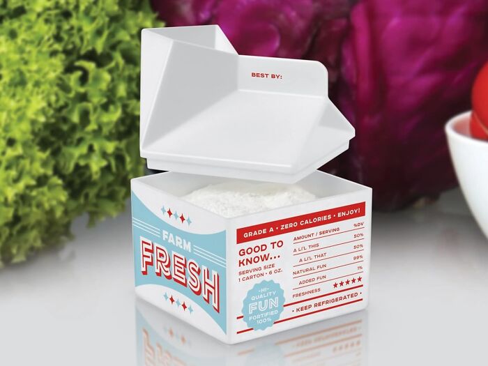 Genuine Fred milk carton design, origami-style, with vibrant farm fresh branding, near vegetables.
