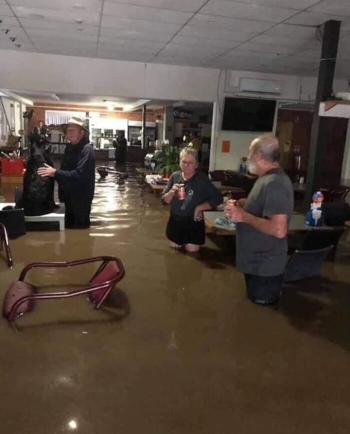 Flooded room with people standing in waist-deep water, showing nature's powerful and terrifying force.