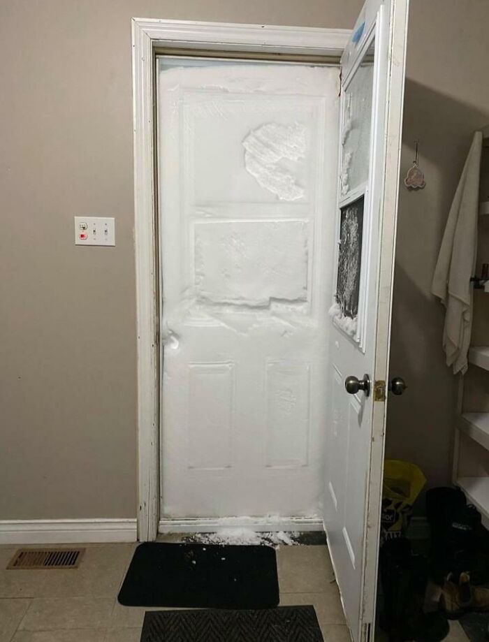 Door almost buried by snow, illustrating nature's powerful and terrifying force.