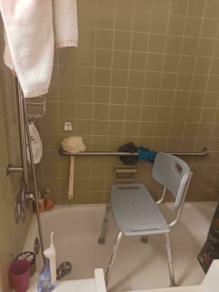 Shower chair and grab bar in a bathtub, showcasing embraced "old people" habits for safety and comfort.