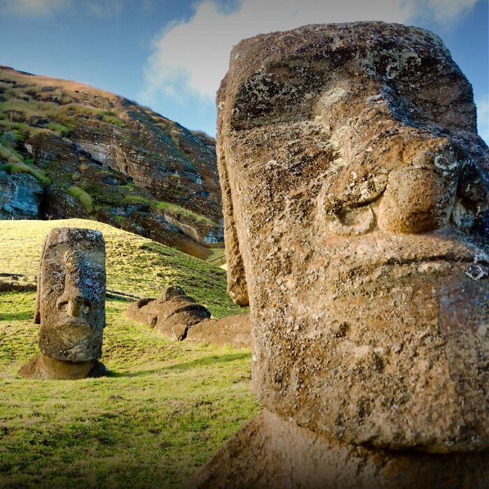 Ancient stone statues on a grassy hillside, showcasing historical preservation.