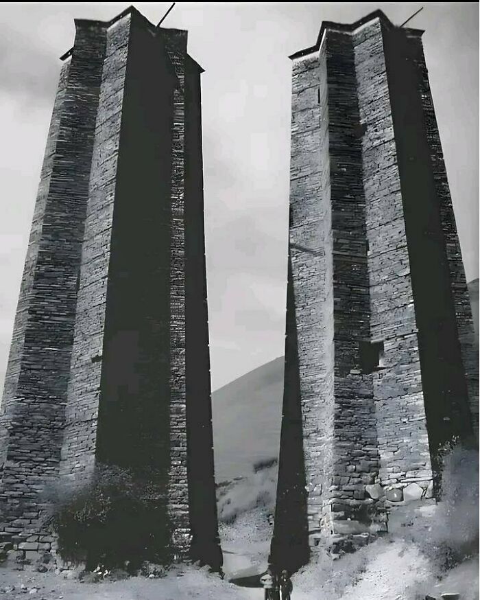 Two ancient stone towers stand tall against a cloudy sky, showcasing preserved architecture from the past.