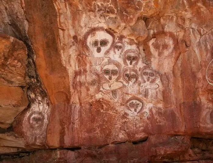 Ancient explorers' rock art featuring abstract figures painted on a cliff face, preserved from the past.