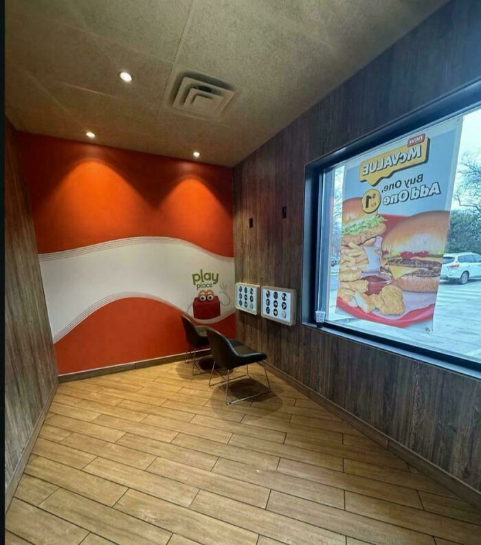 Modern life dull play area with two chairs, minimal decor, and fast food advertisement seen through window.