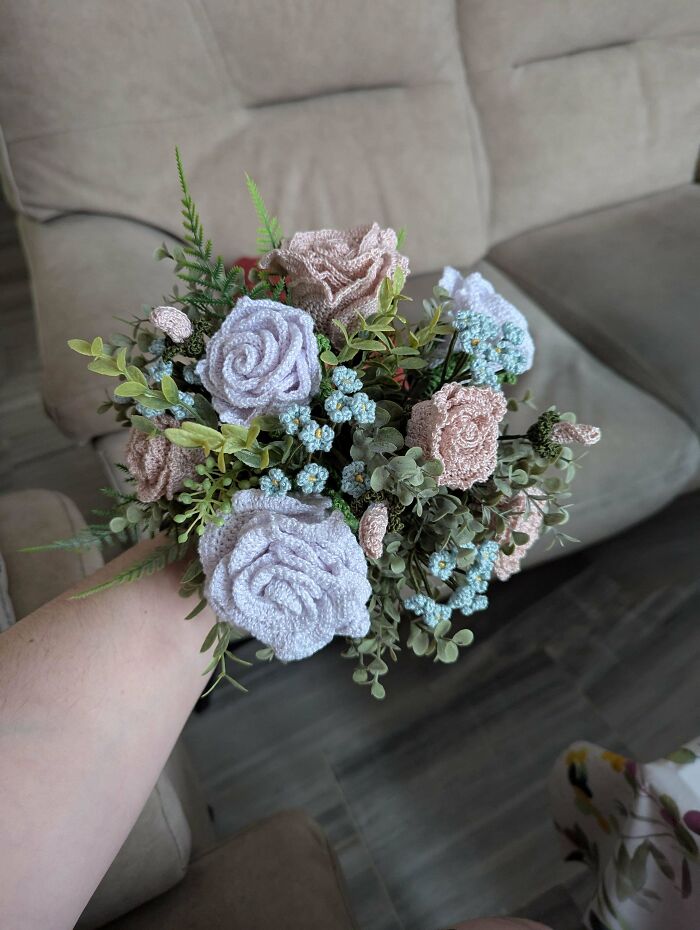 Crochet enthusiasts handmade intricate bouquet of crocheted flowers mixed with greenery, showcasing incredible crochet craftsmanship.