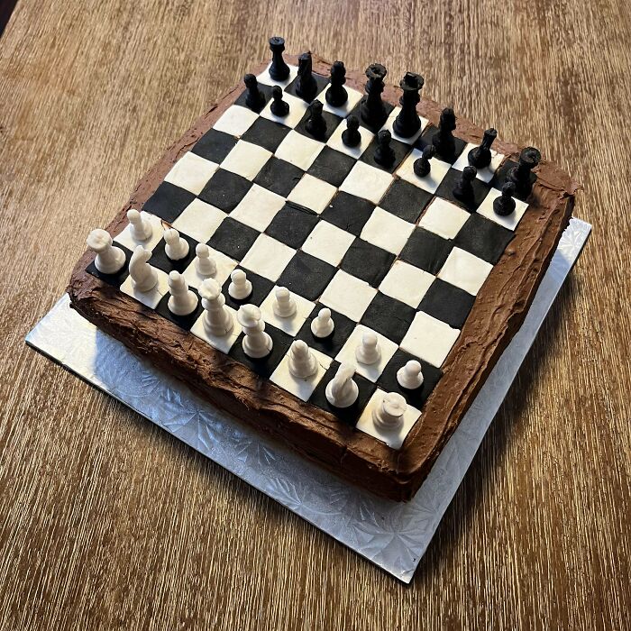 Chess board cake with detailed black and white pieces on chocolate frosting showcasing incredible bakes creativity.