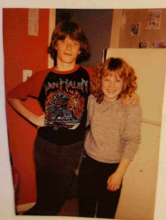 Vintage candid glimpse into the past showing two teenagers posing indoors with one wearing a Van Halen band shirt.