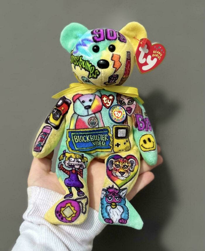Colorful 90s-themed Beanie Baby bear with nostalgic patches including Blockbuster, Game Boy, and vintage cartoon characters.