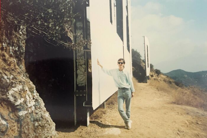 Man standing behind the famous Hollywood sign, providing a new perspective on the iconic landmark.
