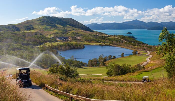 Golfers enjoying a breathtaking course with stunning coastal and mountain views, showcasing global golfing destinations.