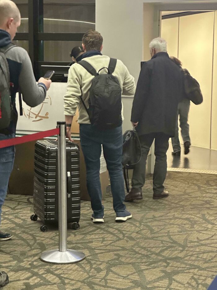 Airline baggage fail as a man waits in line with a damaged suitcase in airport.