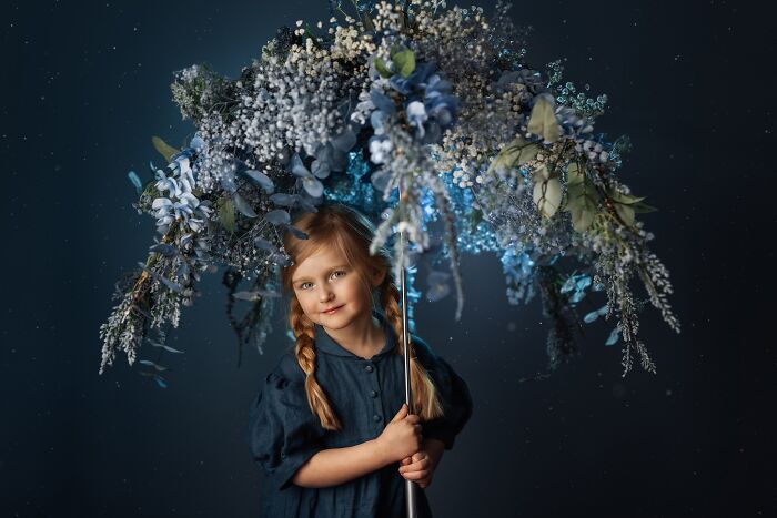 Girl with braided hair under a floral umbrella, capturing the magic of childhood.