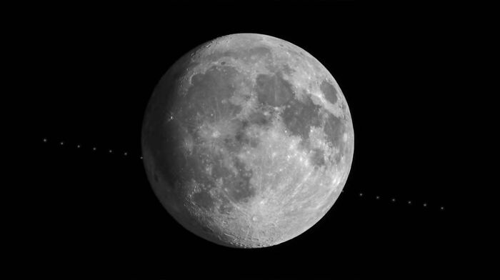 Astrophotography featuring the moon with a satellite trail crossing its surface against a dark night sky.