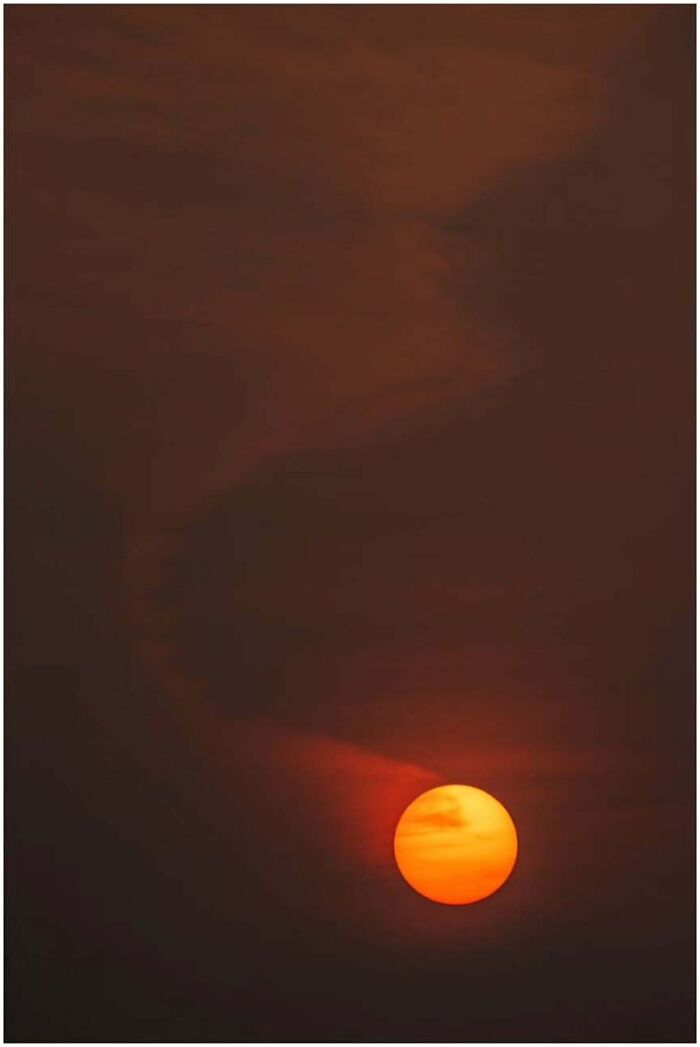 Astrophotography: Vibrant sunset creating a dramatic silhouette against a dark sky with swirling clouds.