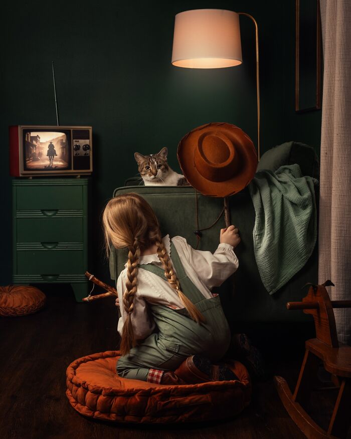 Child with plaited hair playing in a cozy room, a cat watching from the couch; a glimpse into the magic of childhood.