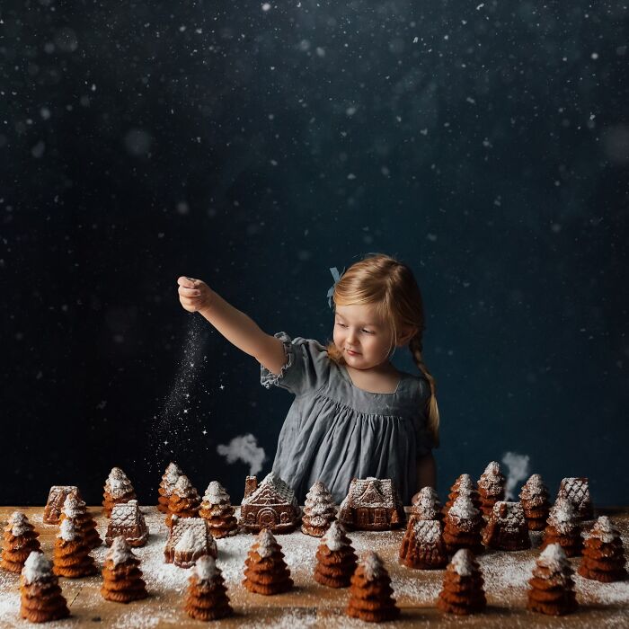 A child sprinkles powdered sugar over gingerbread houses, capturing the magic of childhood through a mother's lens.