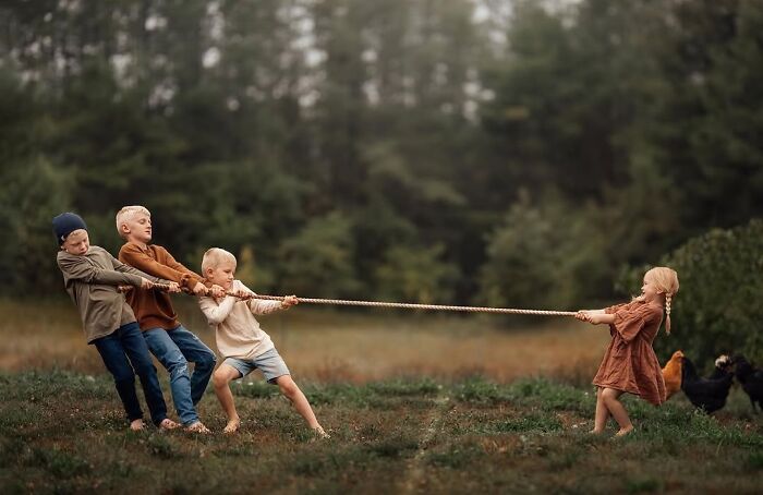 Children playing tug-of-war in a field, showcasing the magic of childhood through a mother’s lens.