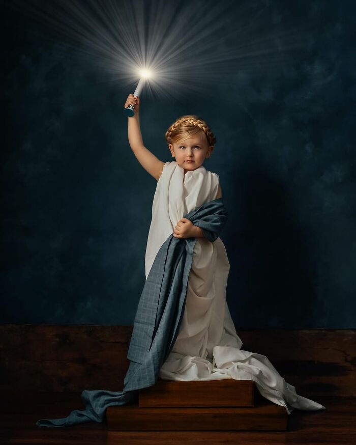 A child dressed in a toga stands holding a glowing wand, capturing the magic of childhood.