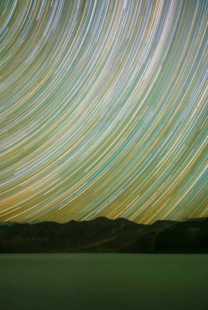 Star trails over a mountain landscape, showcasing mesmerising astrophotography with vivid colors and long exposures.