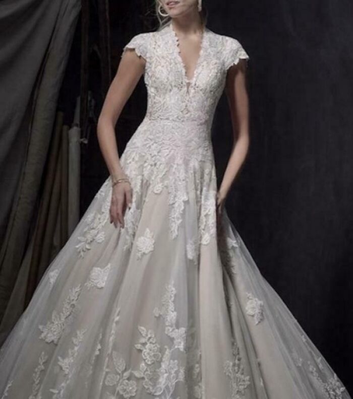 A bride wearing an elegant, vintage-style white wedding dress with lace details and cap sleeves.